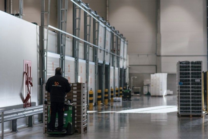 De gang langs de rijpkamers, met een medewerker op een elektrische palletwagen